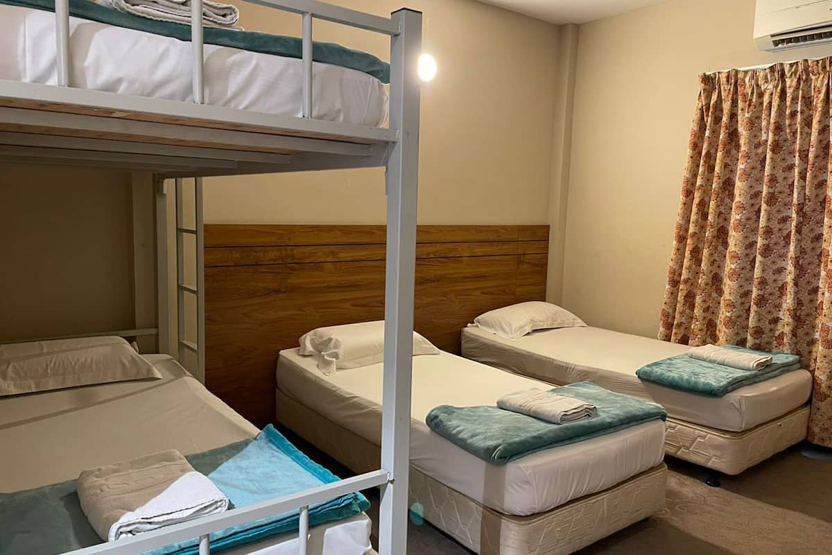 A bunk bed room with two single beds, a wooden headboard, and a floral curtain.