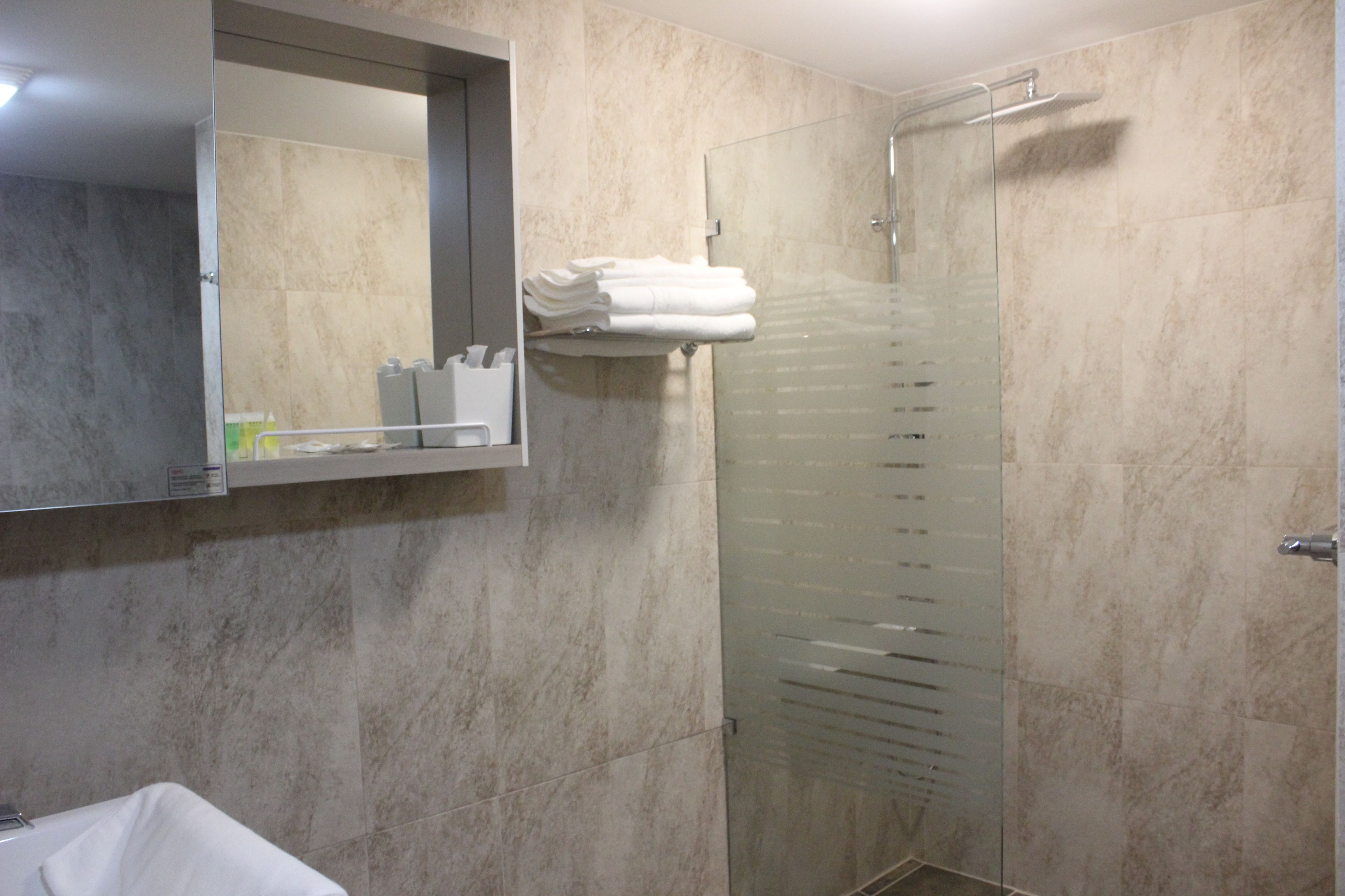 Un bagno moderno con box doccia in vetro, lavabo incassato e specchio sopra il lavabo.