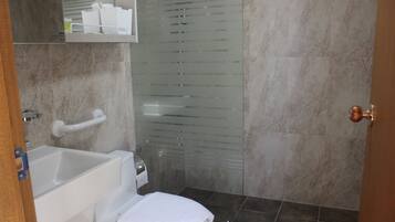 Kylpyhuone, jossa on kylpyamme, wc ja lasinen suihkukaappi.