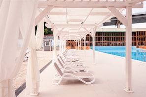 Alberca al aire libre, sombrillas en la alberca y camastros