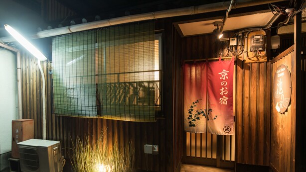A traditional Japanese building with a wooden exterior, a sliding door with a red banner, and a small air conditioning unit outside. - Ikenoya (Kyoto)