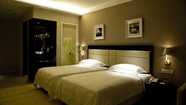 Habitación de hotel con dos camas, un minibar, un baño y una mesita de noche con teléfono.
