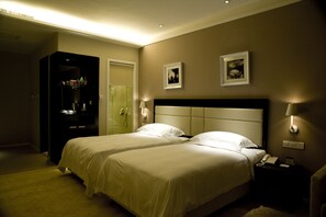 A hotel room with two beds, a minibar, a bathroom, and a nightstand with a phone. - KaiMan Hotel (Zhuhai)