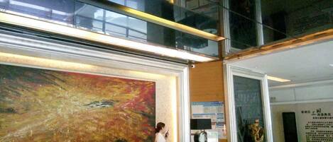 A reception area with a large abstract painting, a reception desk, and a digital screen.