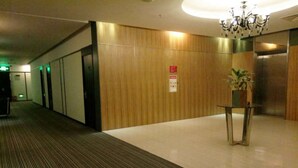 Un vestíbulo de hotel con una pared de madera, una mesa de vidrio con una planta y un candelabro.