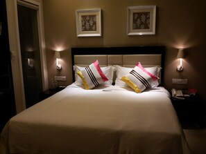 A hotel room with a bed, two wall-mounted lamps, and two framed floral artworks above the bed. - KaiMan Hotel (Zhuhai)