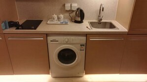 A compact kitchen with a Siemens washing machine, a sink, and a countertop with a kettle and cups. - Beijing Yilejia Apartment (Beijing)