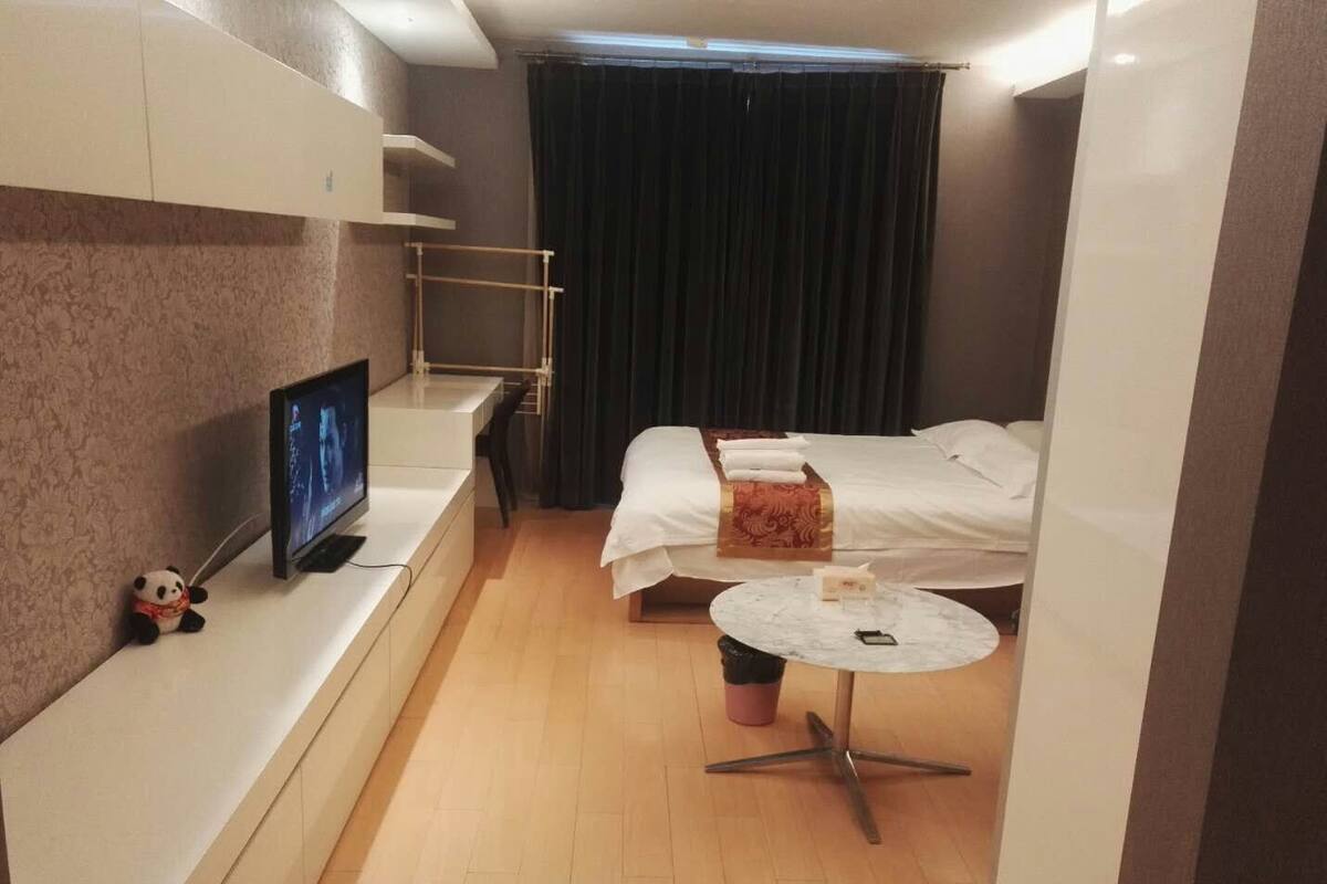 Habitació d'hotel senzilla amb llit, taulella al costat, televisió i taula rodona petita.