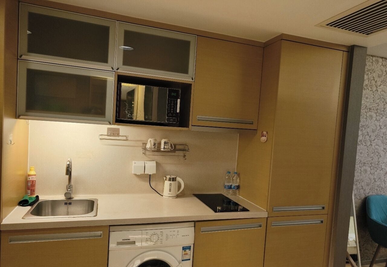 A compact kitchen with a Siemens dishwasher, a microwave, and a kettle on the countertop.