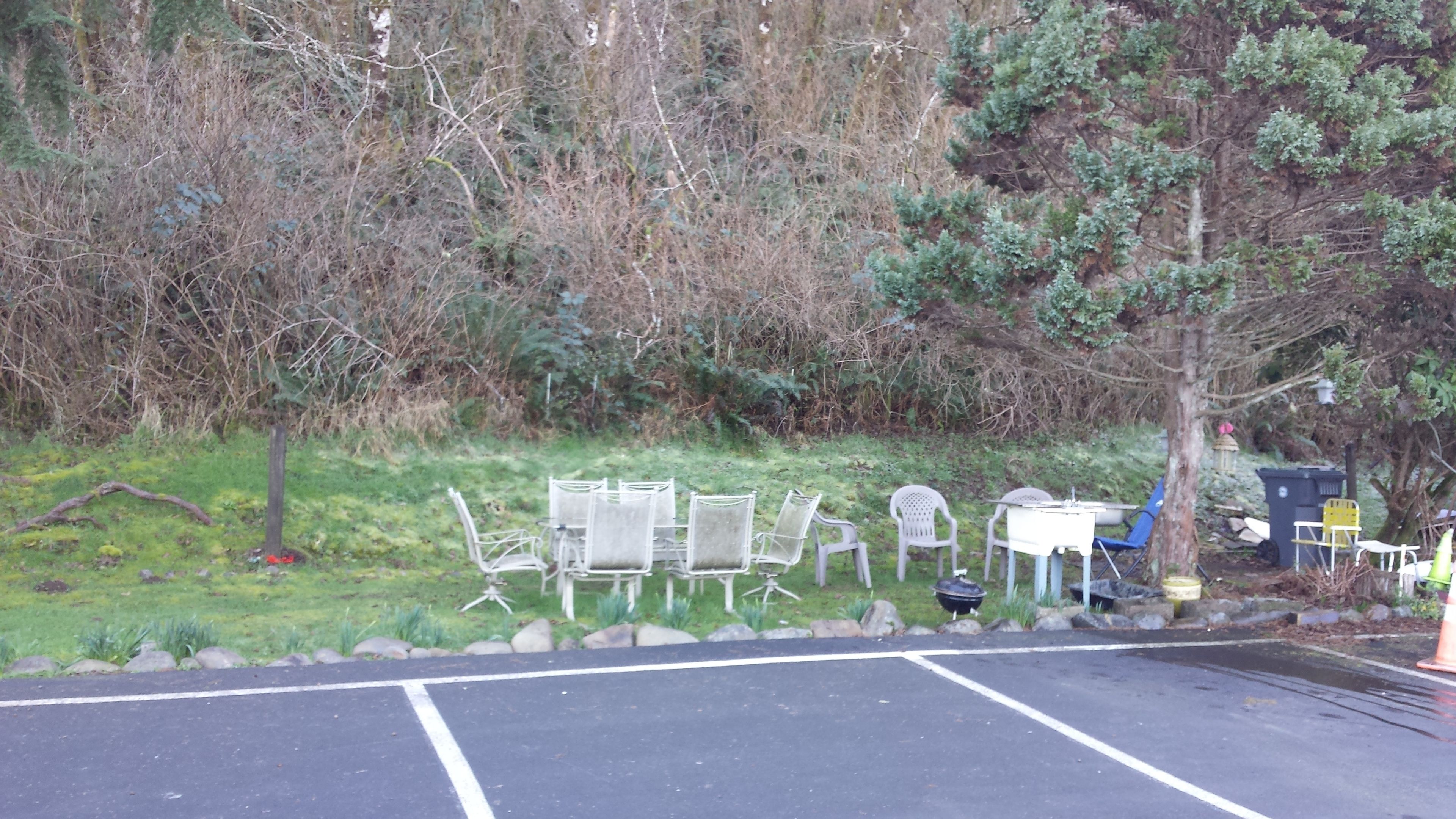 Ein Parkplatz mit einer Reihe weißer Metallstühle und einem kleinen Tisch.
