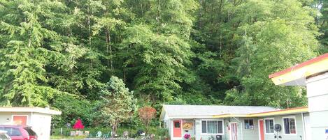 A parking lot with a building that has a porch and a small garden area.