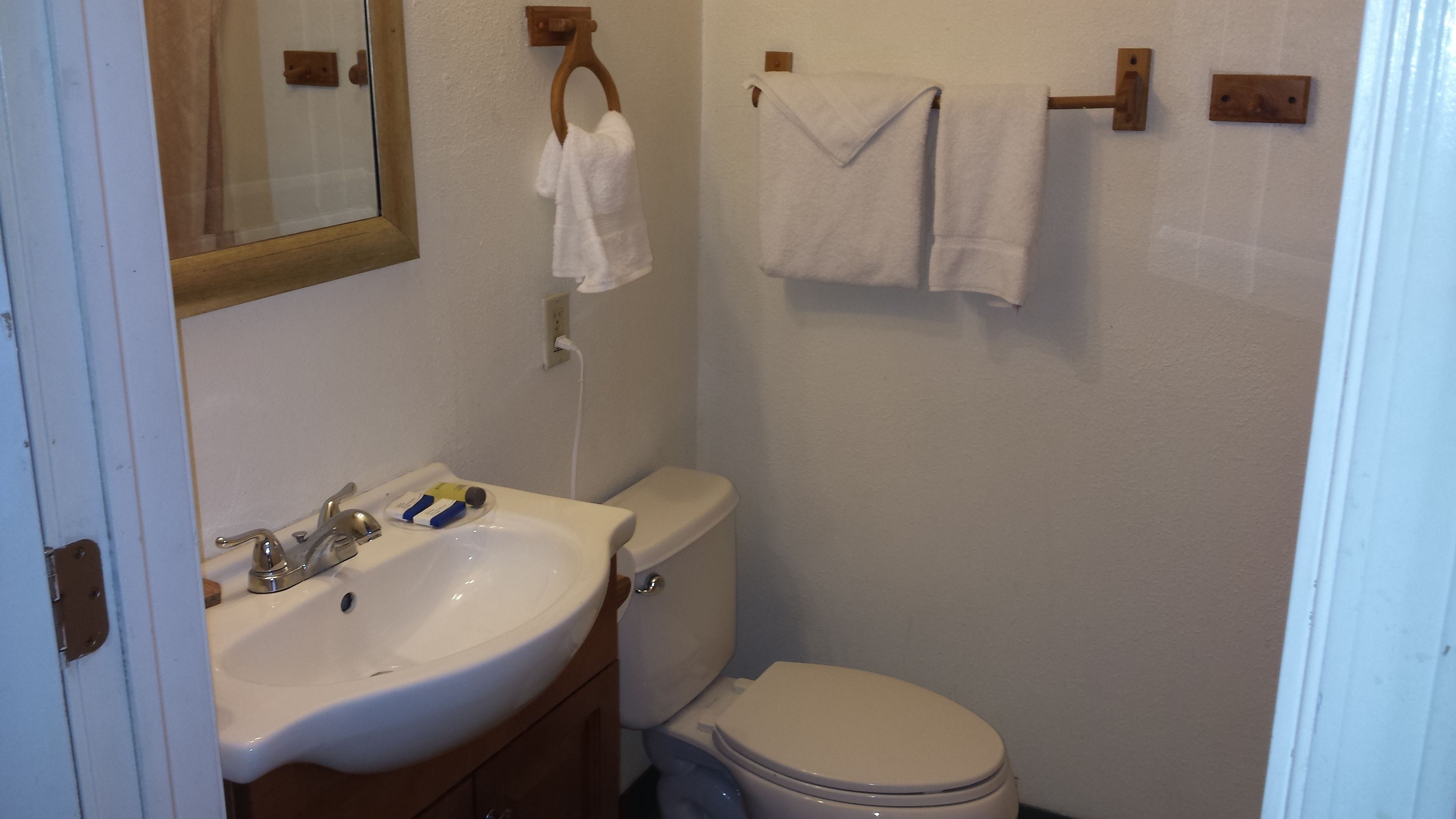 Een badkamer met een witte wastafel, een toilet en twee handdoeken aan een rek.