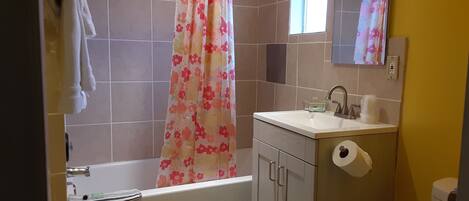 A bathroom with a bathtub, a sink with a mirror, and a toilet.