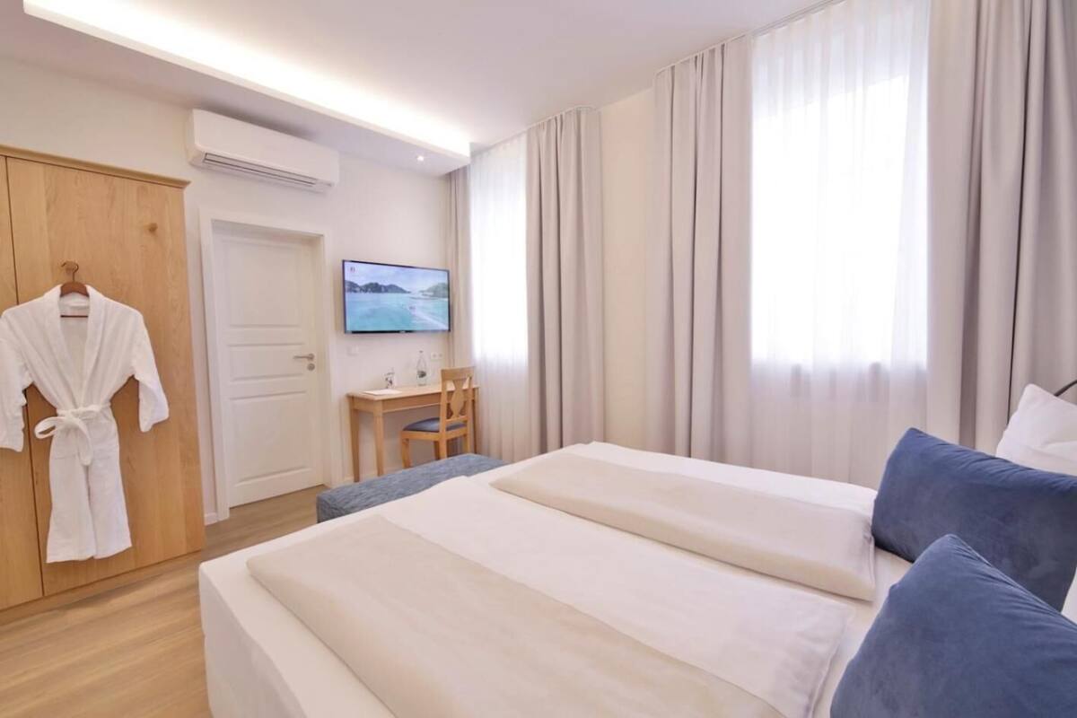 Ein Hotelzimmer mit Bett, Schreibtisch, Stuhl, Fernseher und Kleiderschrank.