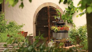 Une porte en bois en forme d’arc, un banc en bois et un jardinier avec des fleurs.