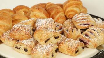 A plate of pastries, including croissants and filled pastries dusted with powdered sugar.