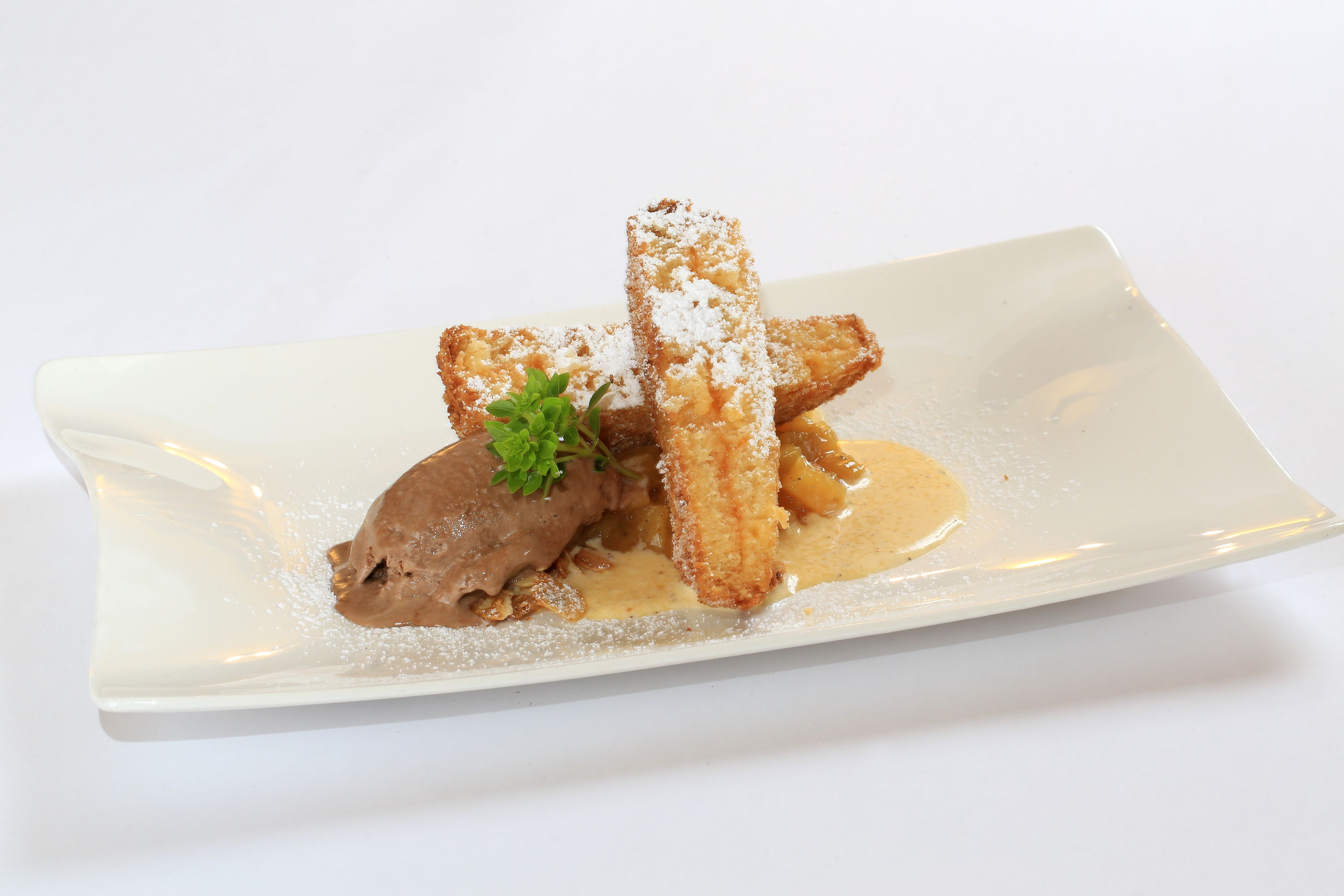 A dessert plate with a pastry, a scoop of ice cream, and a sprig of mint.