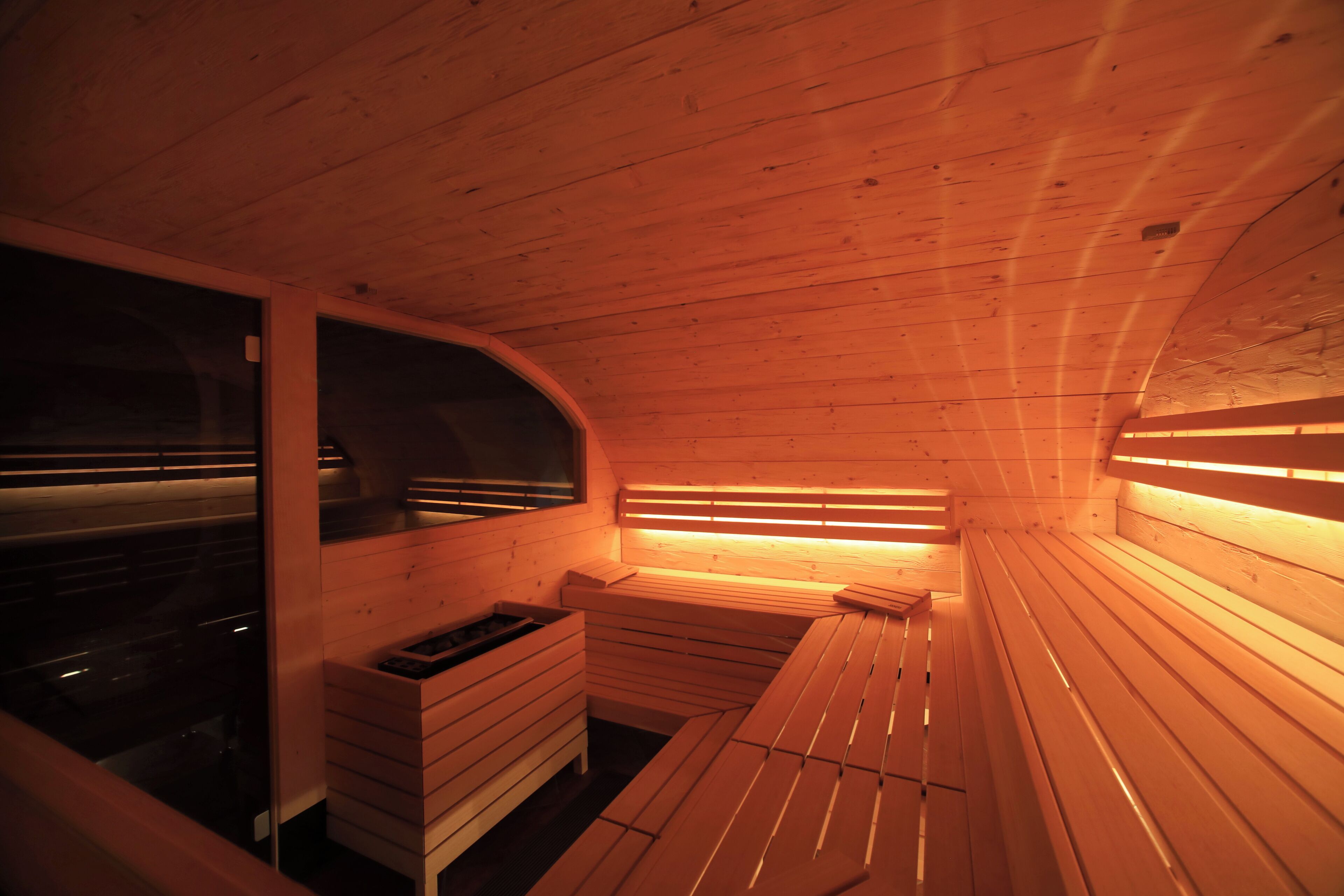 A sauna with wooden benches and benches, a bench with a small table, and a bench with a heater.