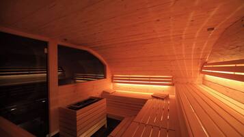 A sauna with wooden benches and benches, a bench with a small table, and a bench with a heater.