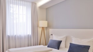 Une chambre d’hôtel avec un grand lit, une lampe de chevet et des rideaux légers.