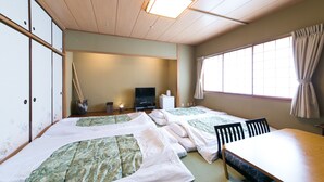 Una habitación de estilo japonés tradicional con tatamis, una mesa baja y un televisor.