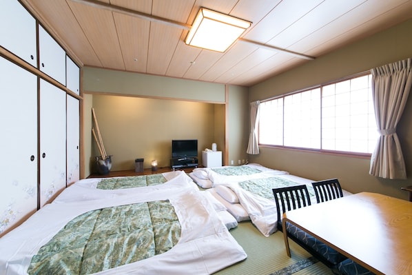 Perinteinen japanilaistyylinen huone, jossa on tatamimatot, matala pöytä ja televisio.