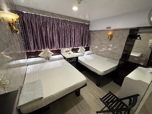A hotel room with two beds, a desk, a chair, a mirror, and a bathroom.