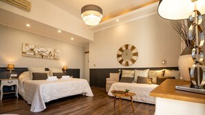 A hotel room with two beds, a wooden floor, a round wall clock, and a small table with a plant. - Hotel Restaurant Le Bellevue (Bormes-Les-Mimosas)