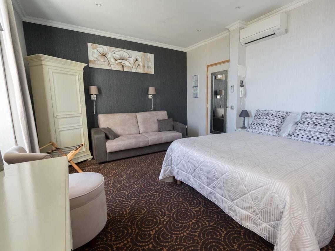 Ein Hotelzimmer mit einem großen Bett, einer Couch, einem Schrank und einem gemusterten Teppich.
