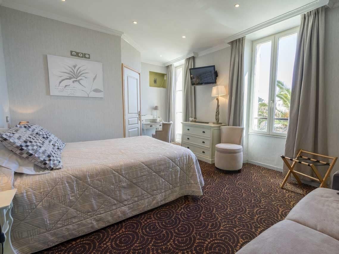 Una habitación de hotel con una cama grande, un escritorio con silla, un televisor y una ventana con cortinas.