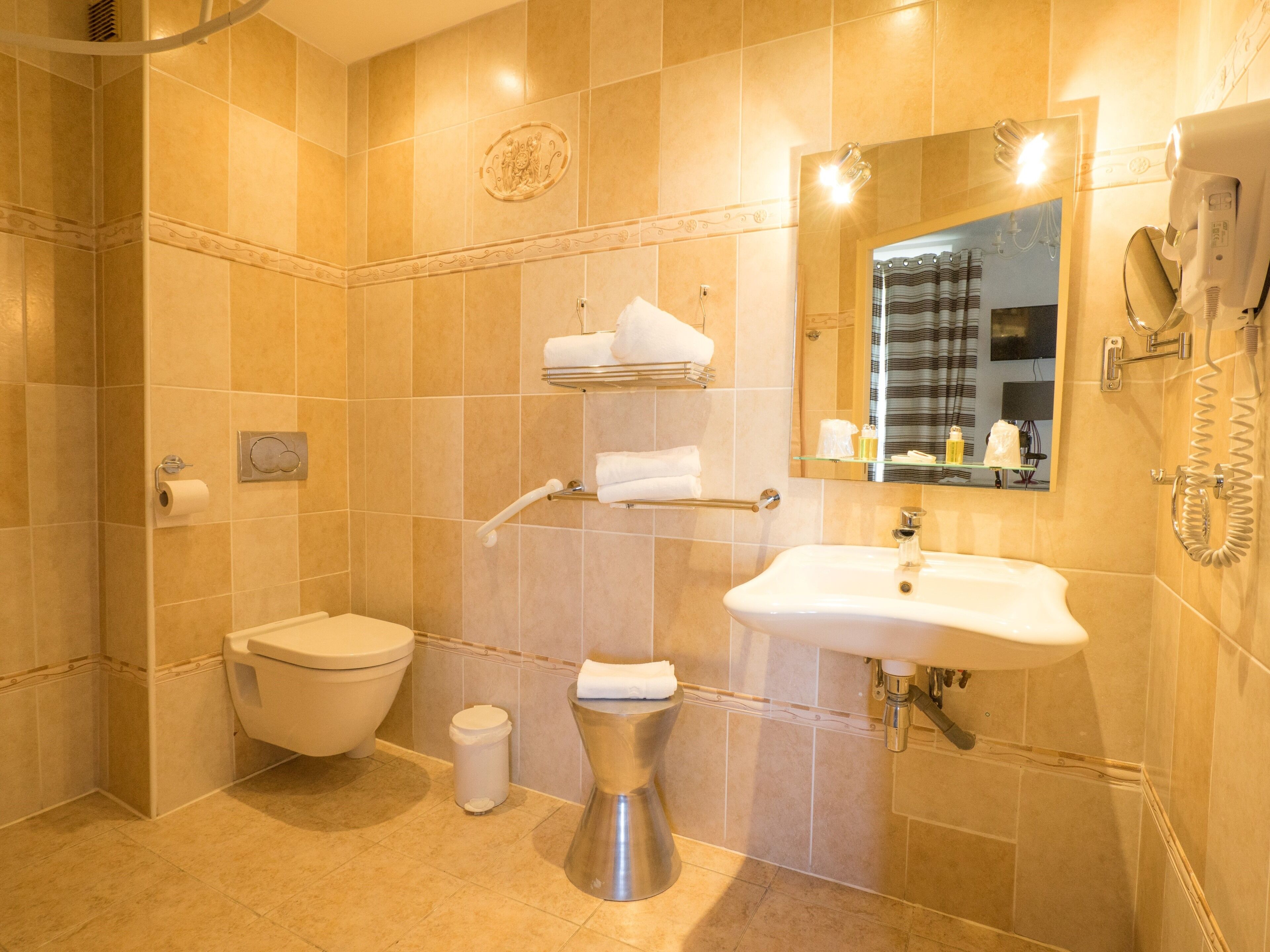 Een badkamer met toilet, bidet, wastafel en spiegel.