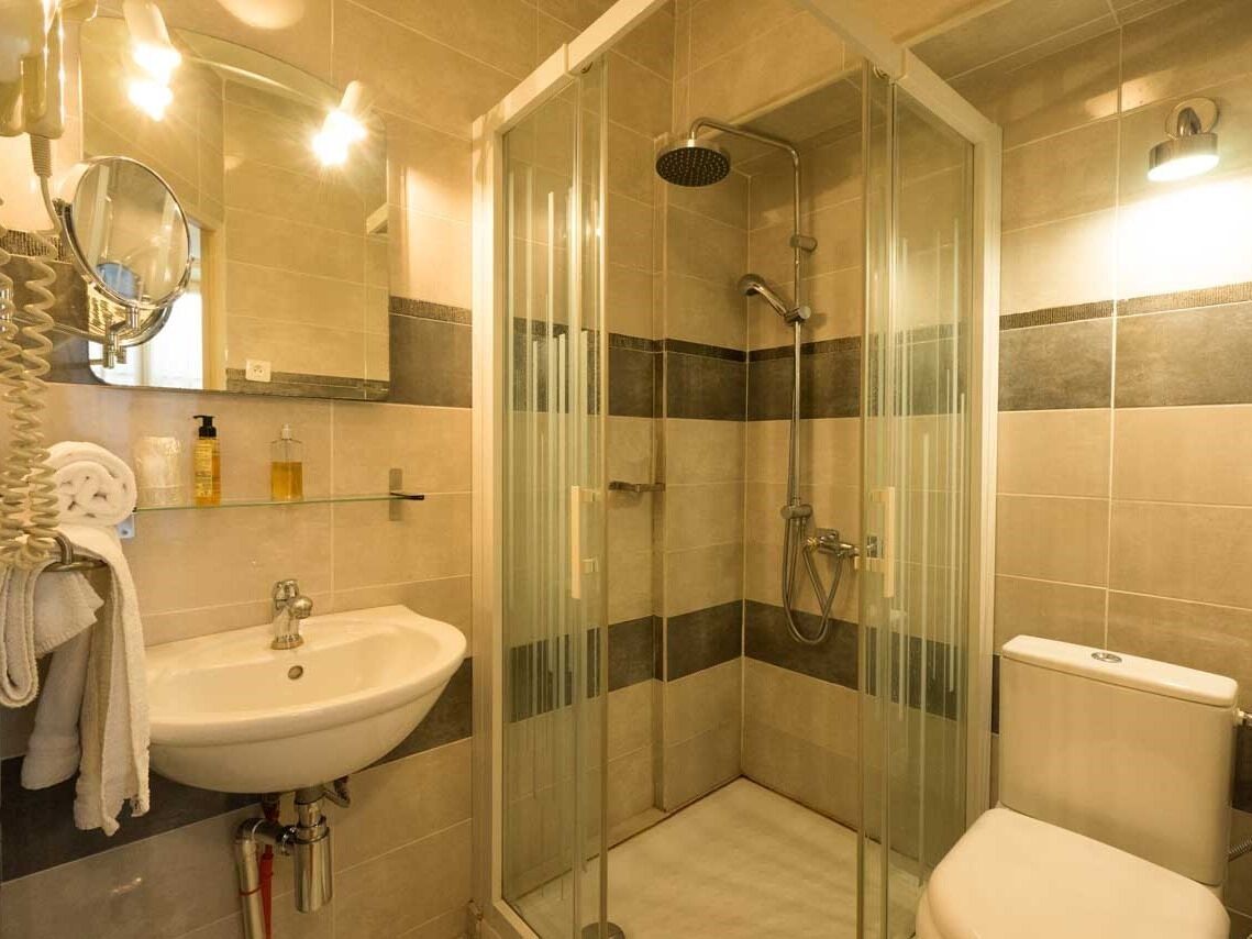 A bathroom with a glass-enclosed shower, a sink, and a toilet.