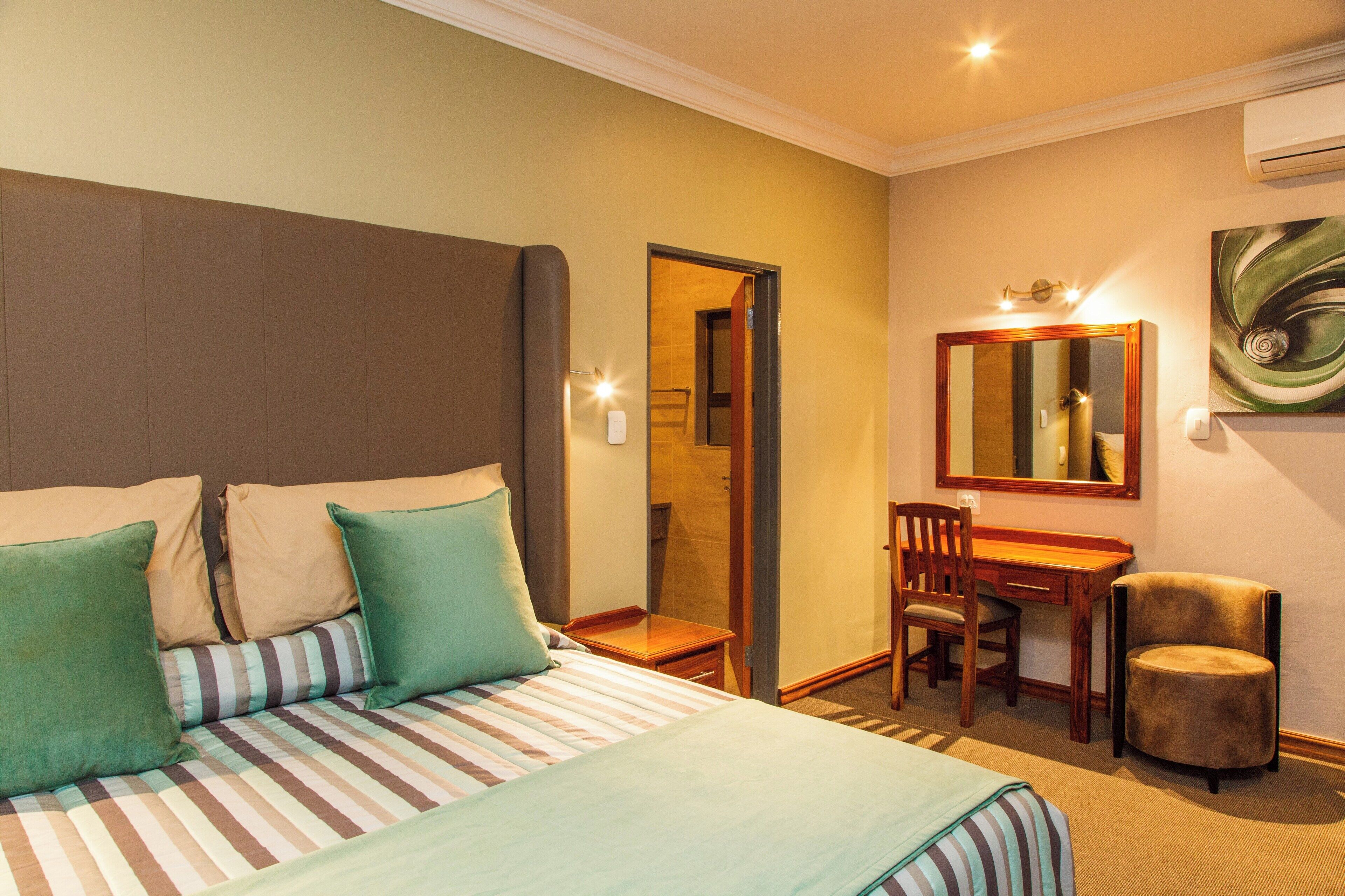 Een hotelkamer met een bed, een bureau, een stoel en een spiegel.