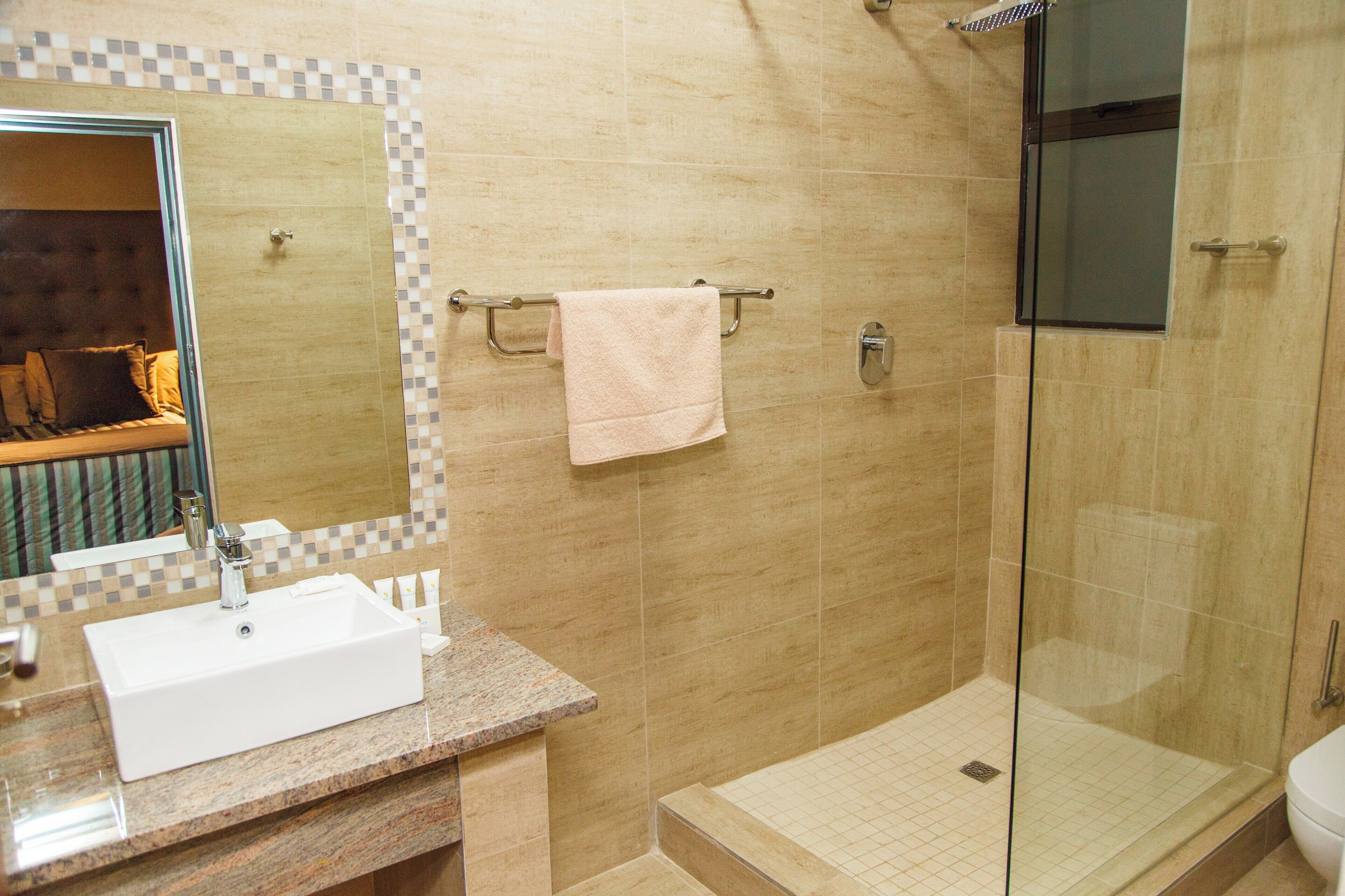 A bathroom with a sink, mirror, towel rack, and glass shower enclosure.