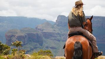 A person riding a horse on a mountain with a view of a canyon.