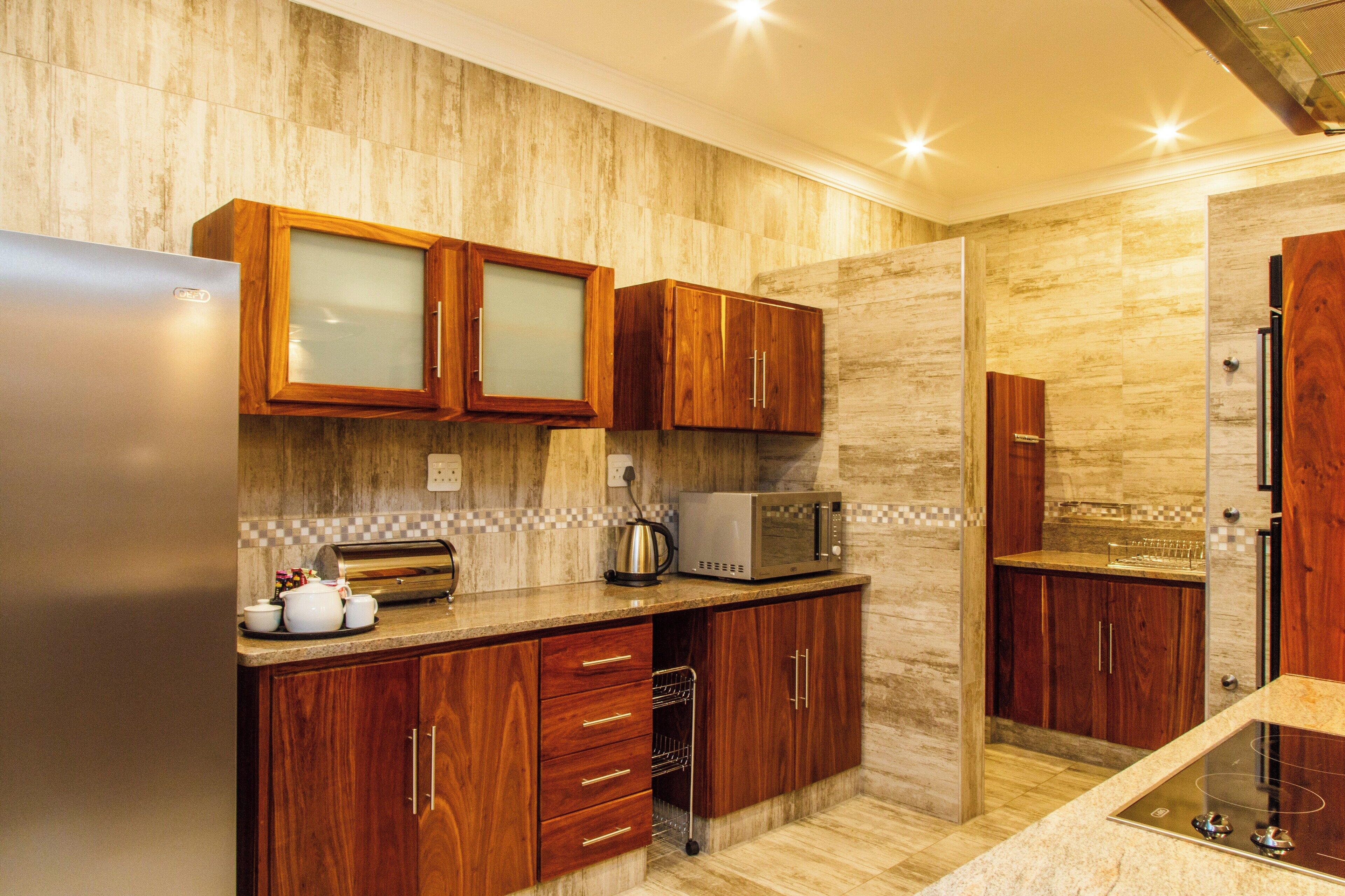 A modern kitchen with wooden cabinets, a built-in microwave, and a stainless steel refrigerator.
