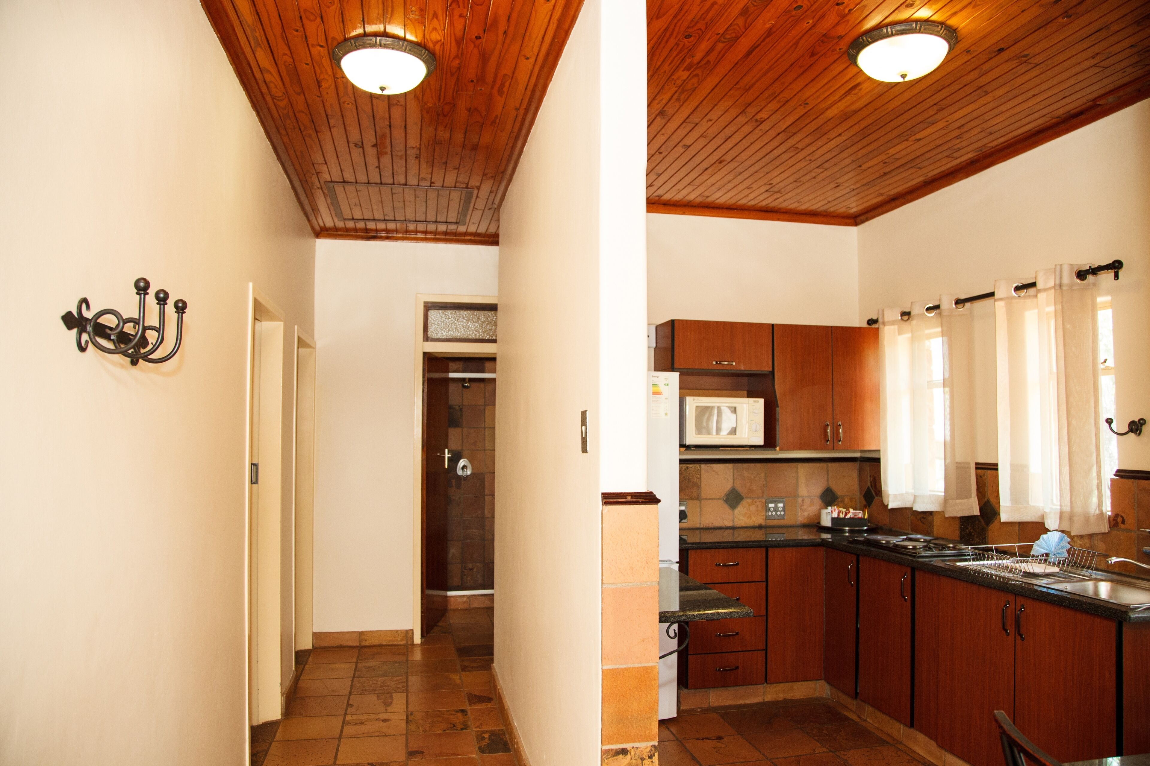 A kitchen with wooden cabinets, a microwave, and a sink.