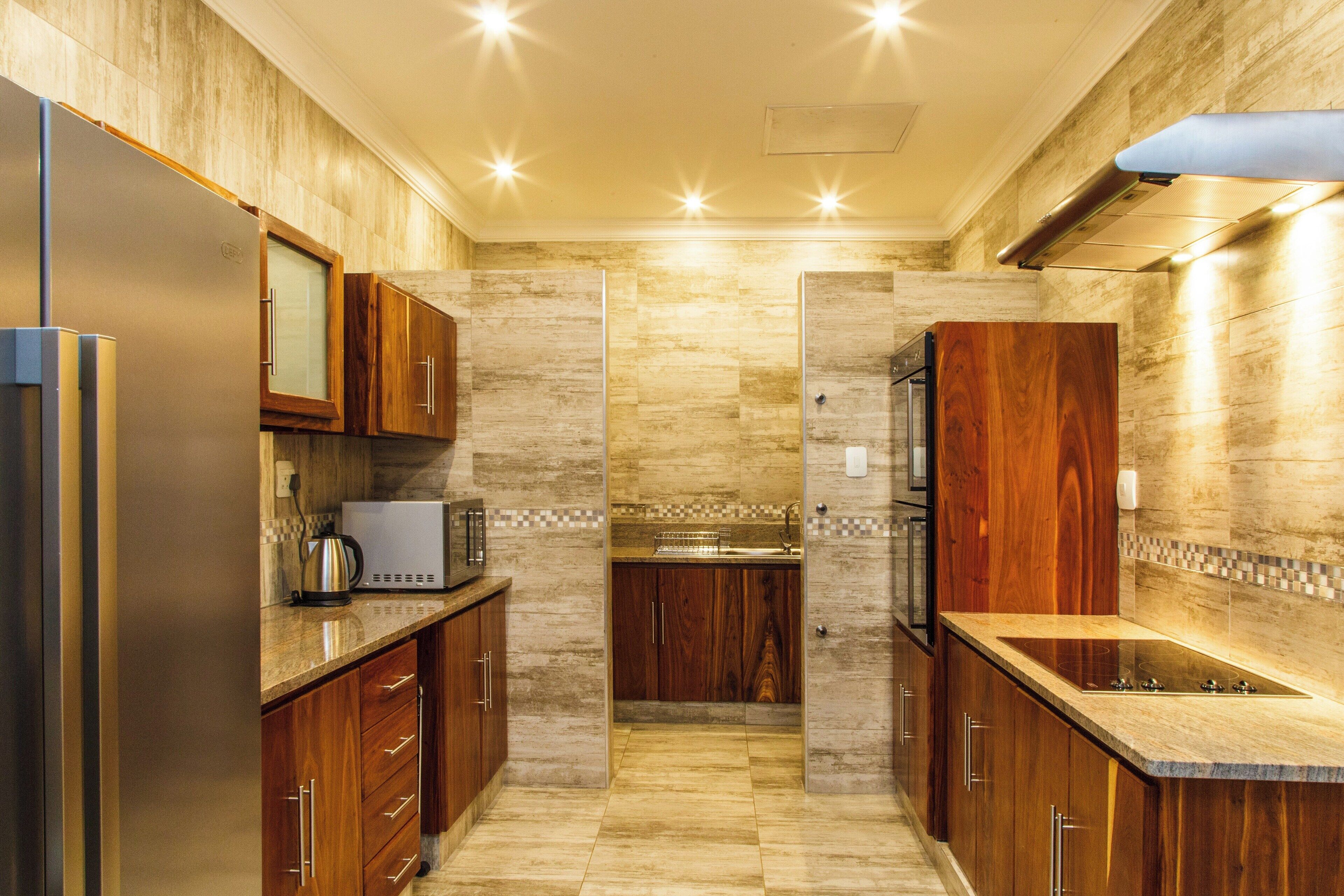 A modern kitchen with wooden cabinets, a stainless steel refrigerator, a microwave, and a built-in oven.