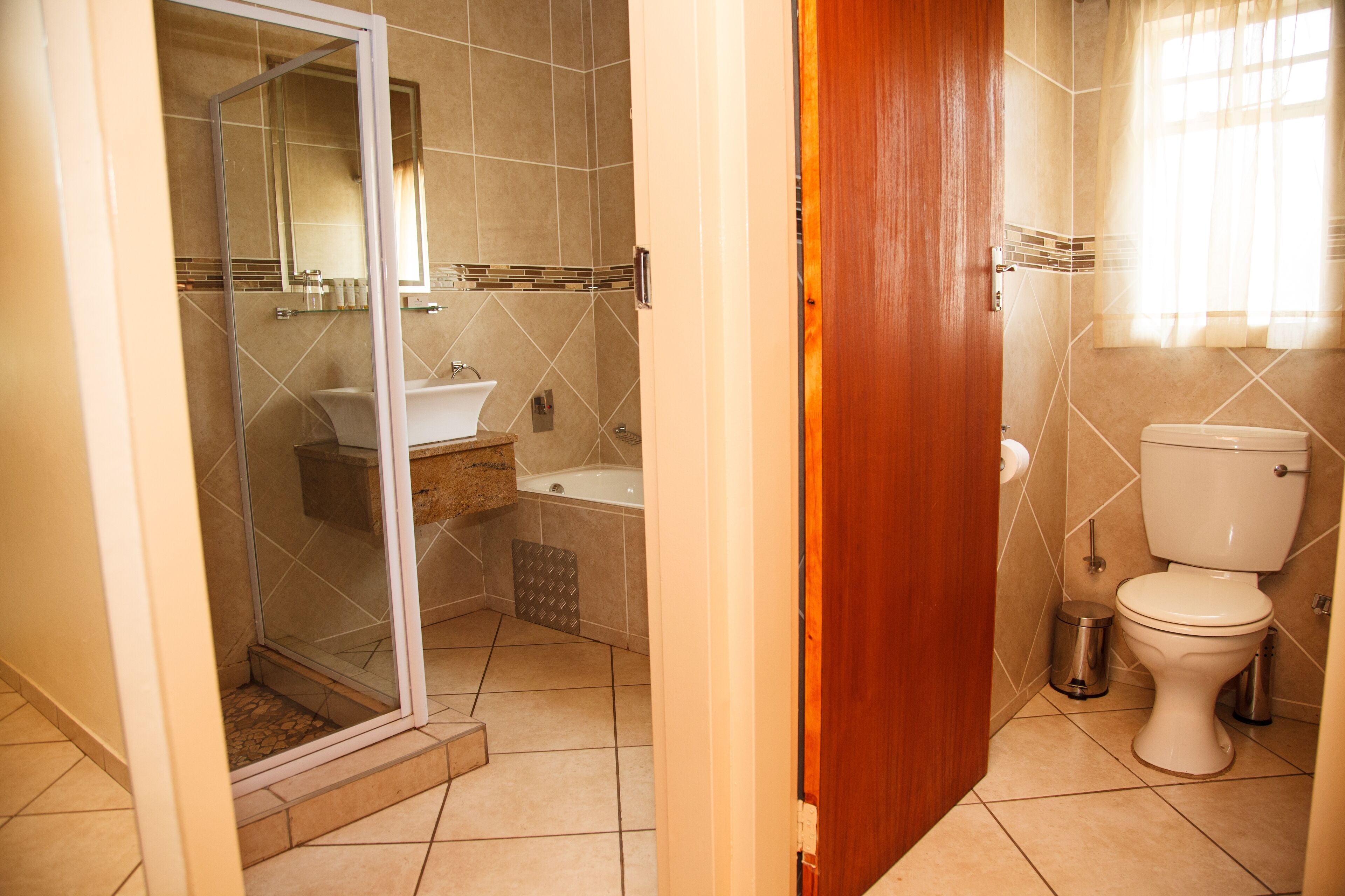 A bathroom with a glass-enclosed shower, a sink, a bathtub, and a toilet.