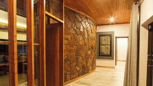 Un couloir avec un mur en pierre, une porte en bois et un tableau encadré accroché au mur.