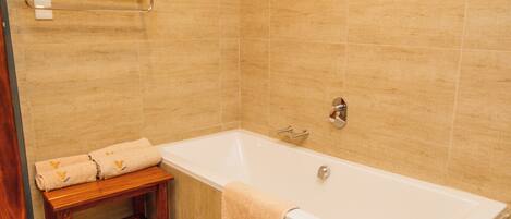 A bathroom with a bathtub, a wooden bench, and a towel rack.