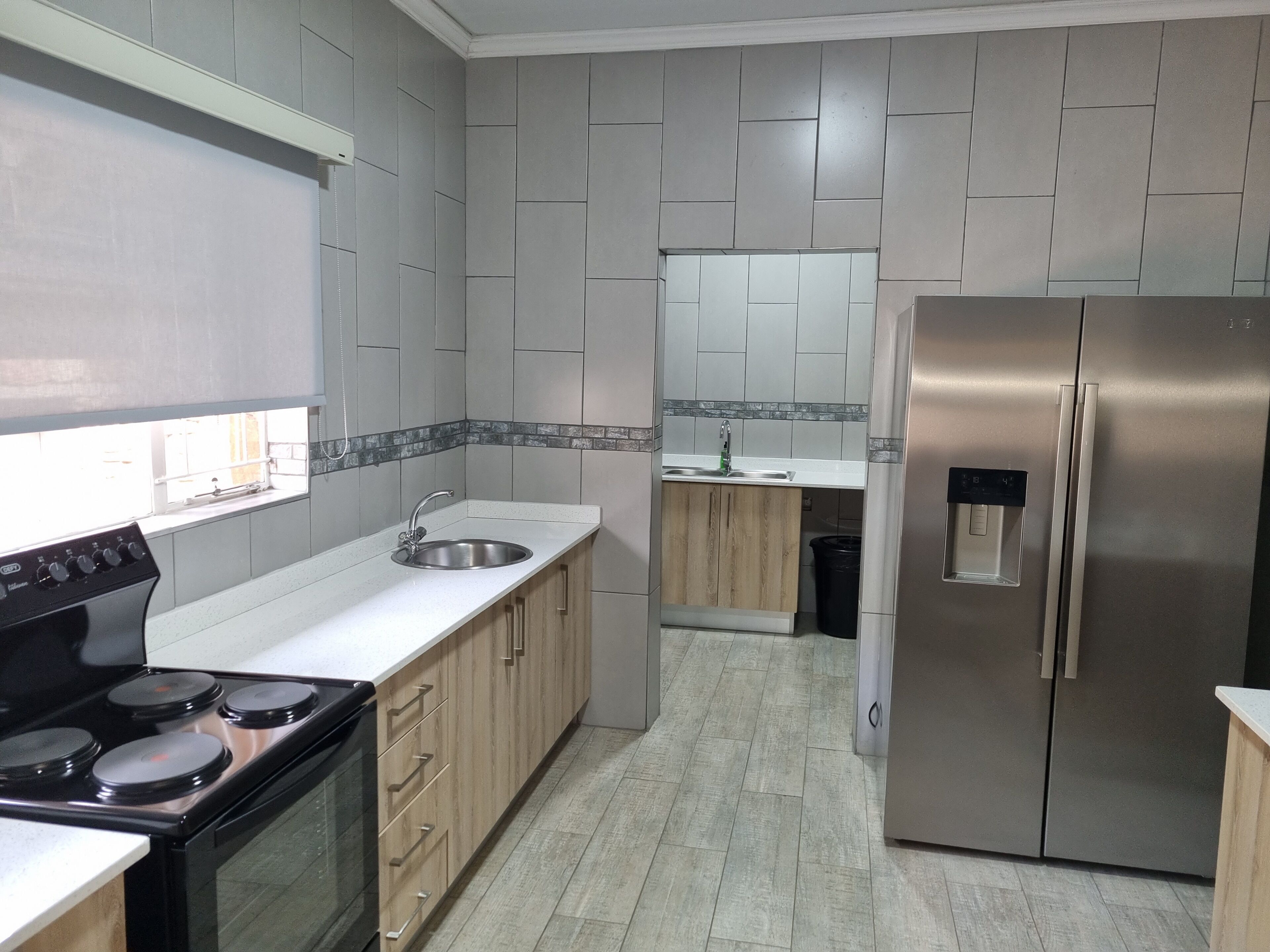 A modern kitchen with a stainless steel refrigerator, a built-in oven, and a sink.