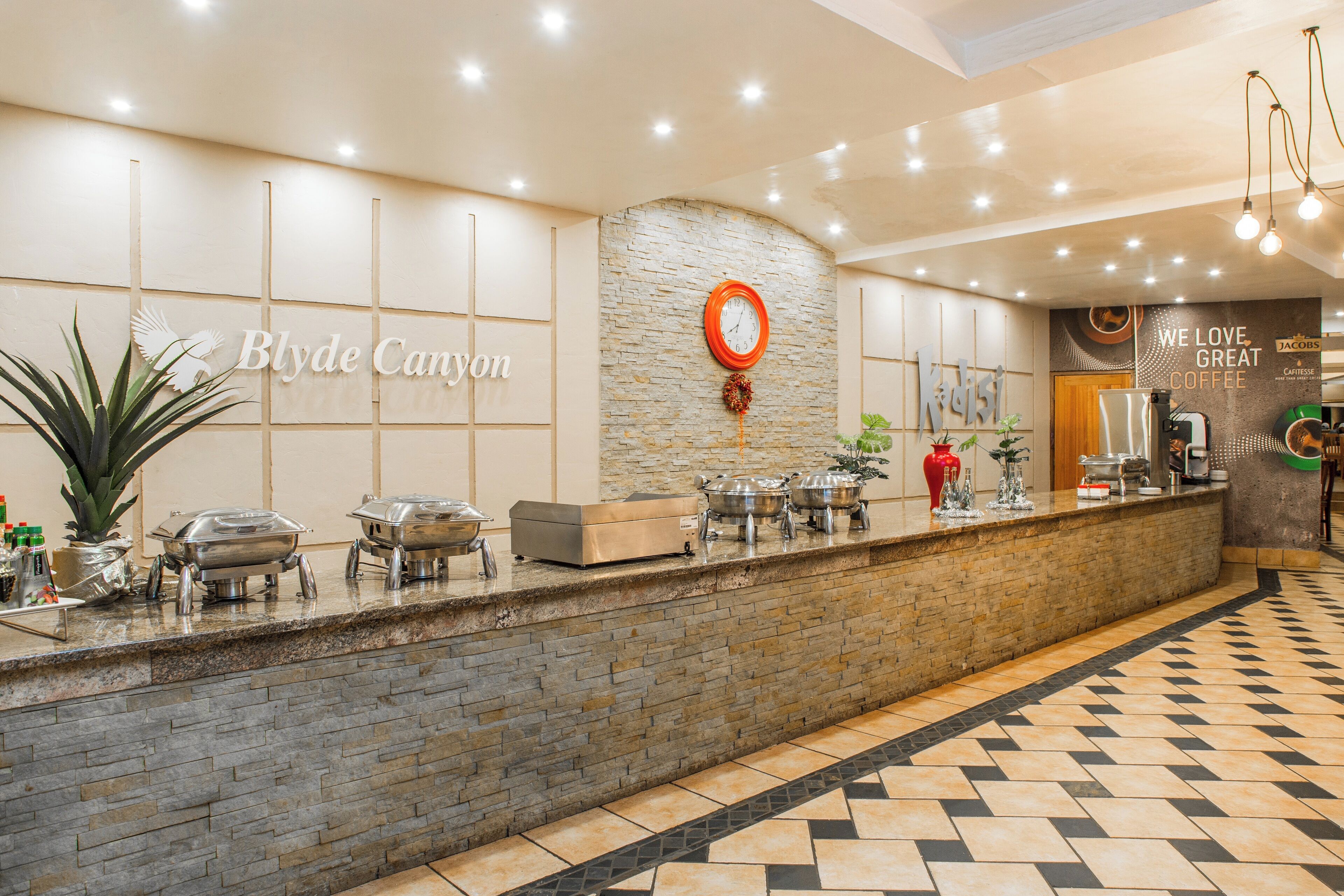 A reception area with a stone wall, a clock, and a sign that reads "Blyde Canyon."