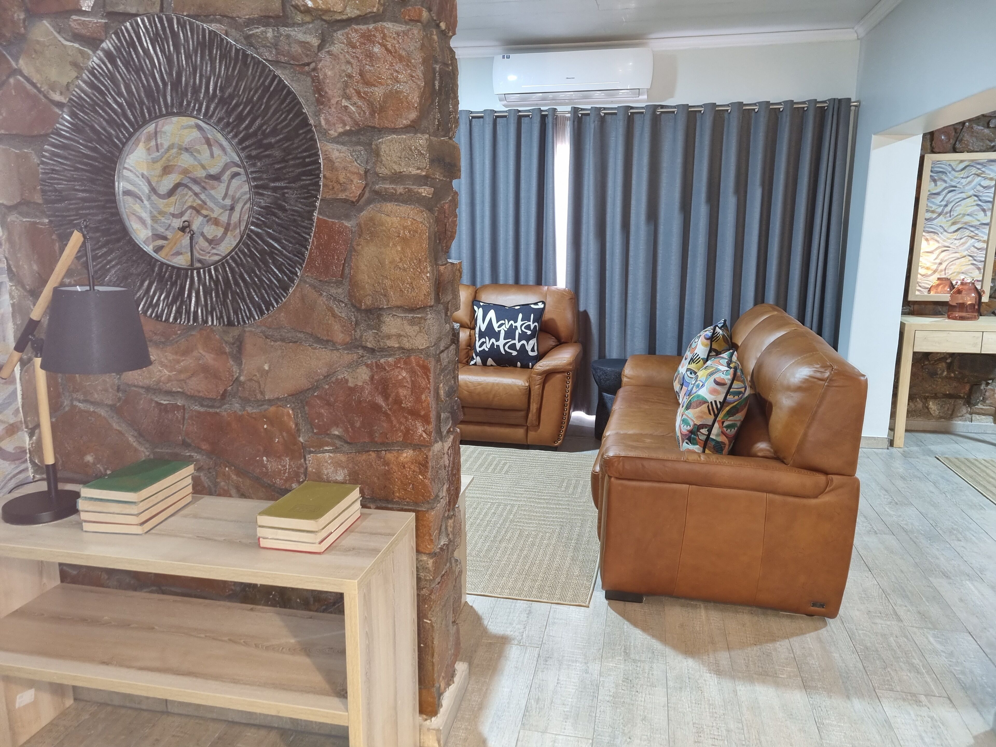A living room with a stone wall, leather sofas, a coffee table, and a lamp.