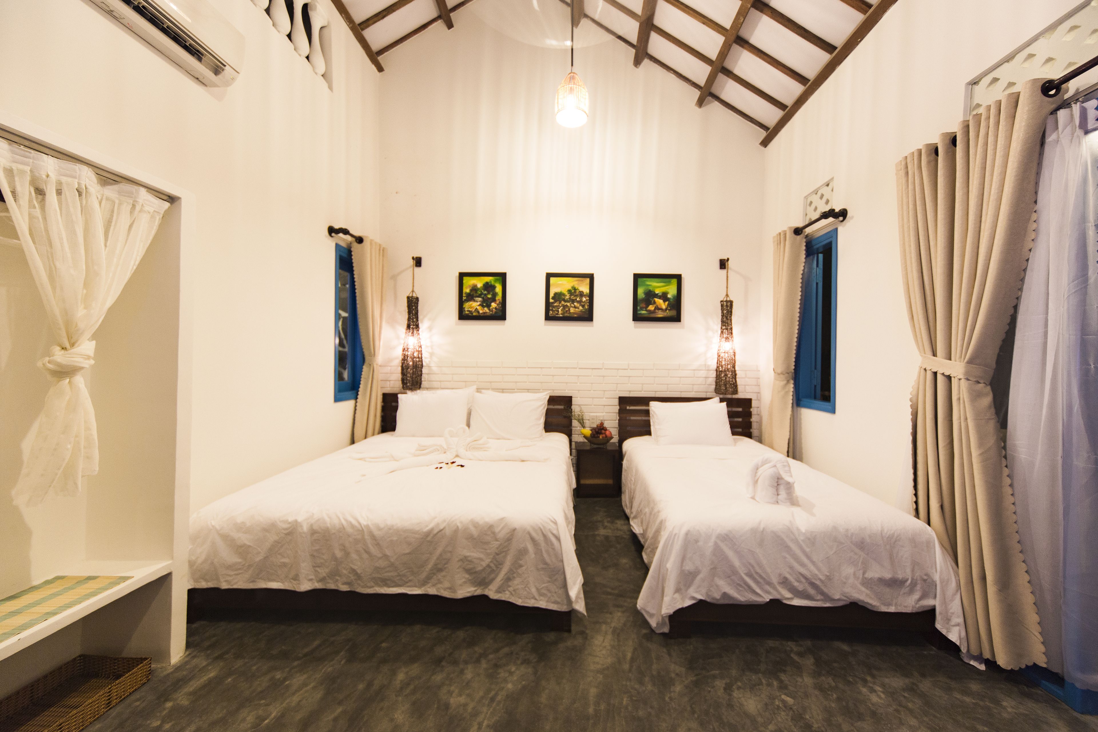 A hotel room with two single beds, a large window with a view, and a ceiling fan.