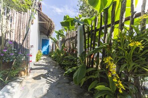 A narrow stone pathway flanked by lush vegetation and a bamboo fence. - Cashew Tree Bungalow (Da Nang)