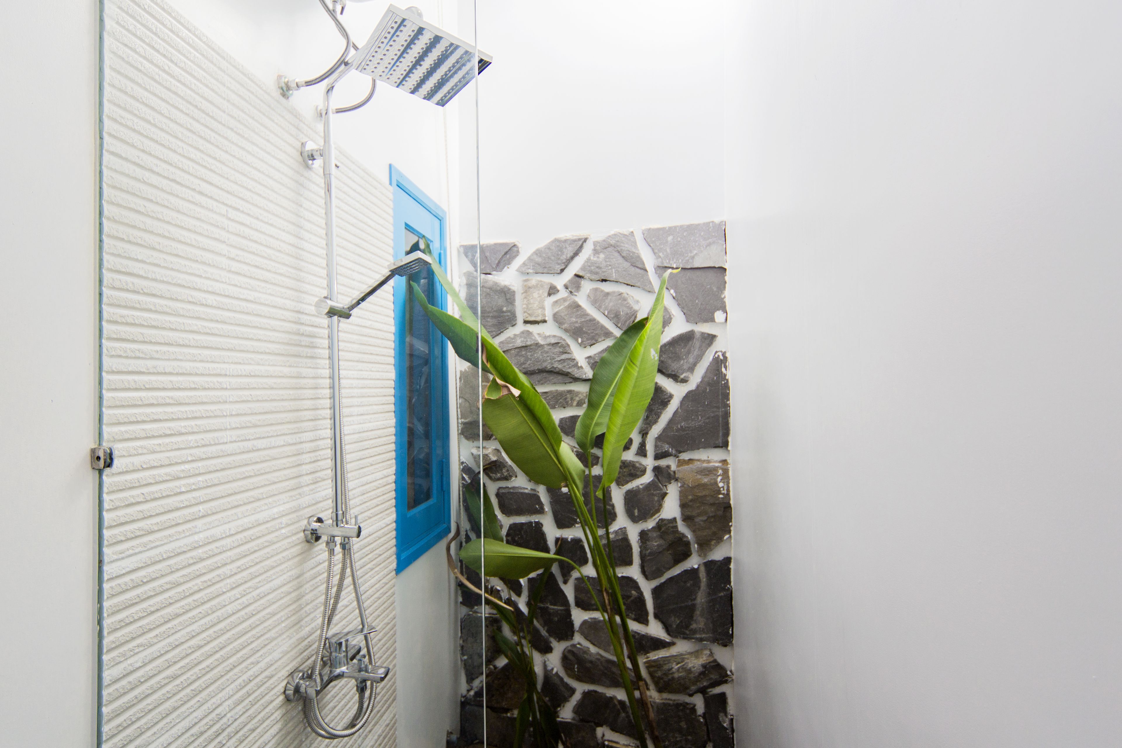 Un baño con ducha, toallero y pared de piedra.