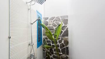 Un baño con ducha, toallero y pared de piedra.