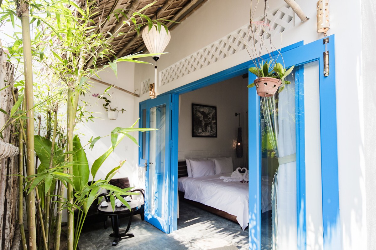 A room with a bed, a chair, and a hanging plant.