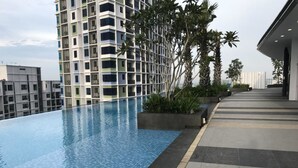 Una piscina en la azotea con vistas a un moderno rascacielos y algunas palmeras.